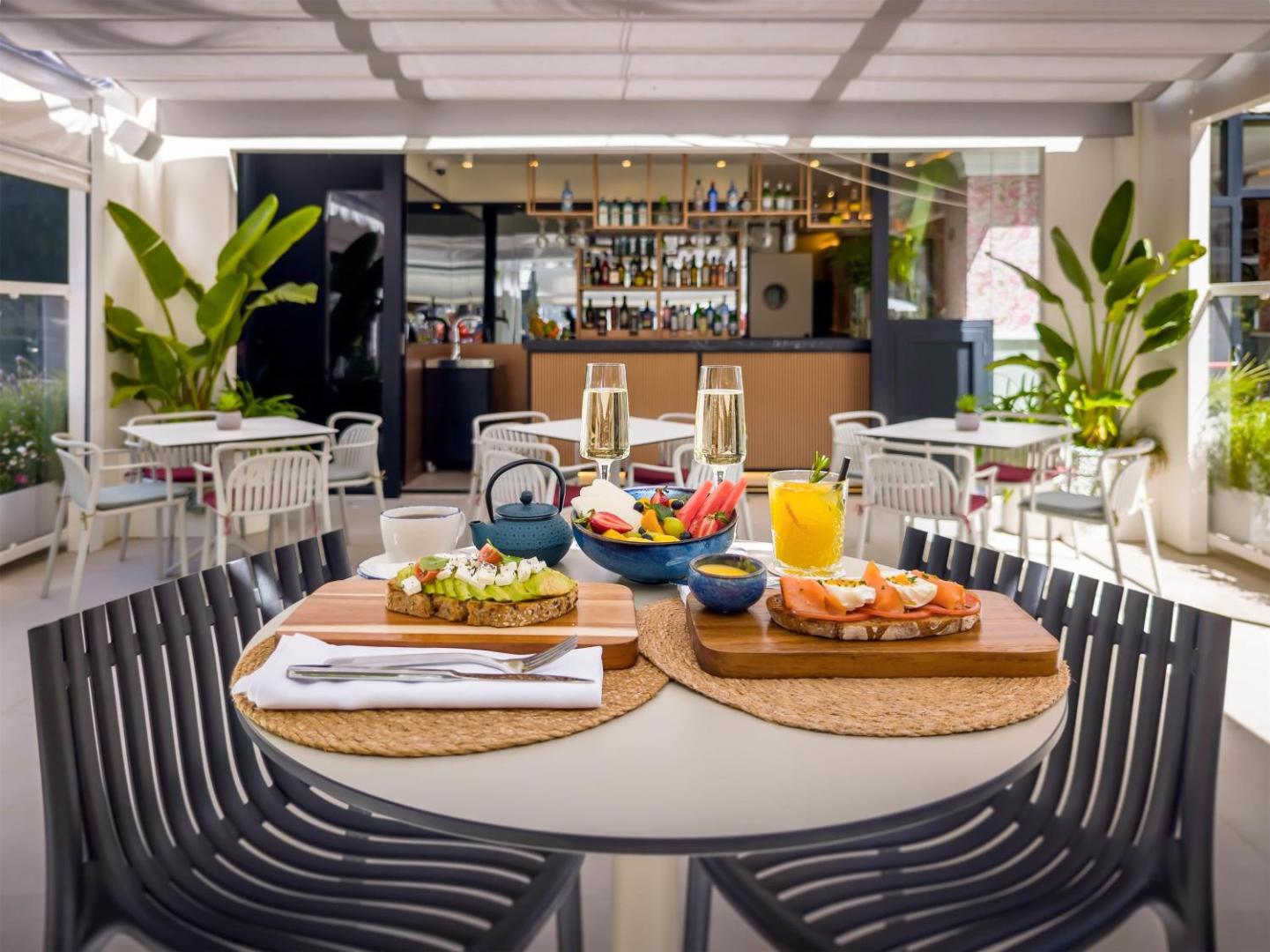 Brokastu galds Occidental Puerto Banus viesnīcas terasē ar avokado maizītēm, augļiem un dzērieniem Marbeljā