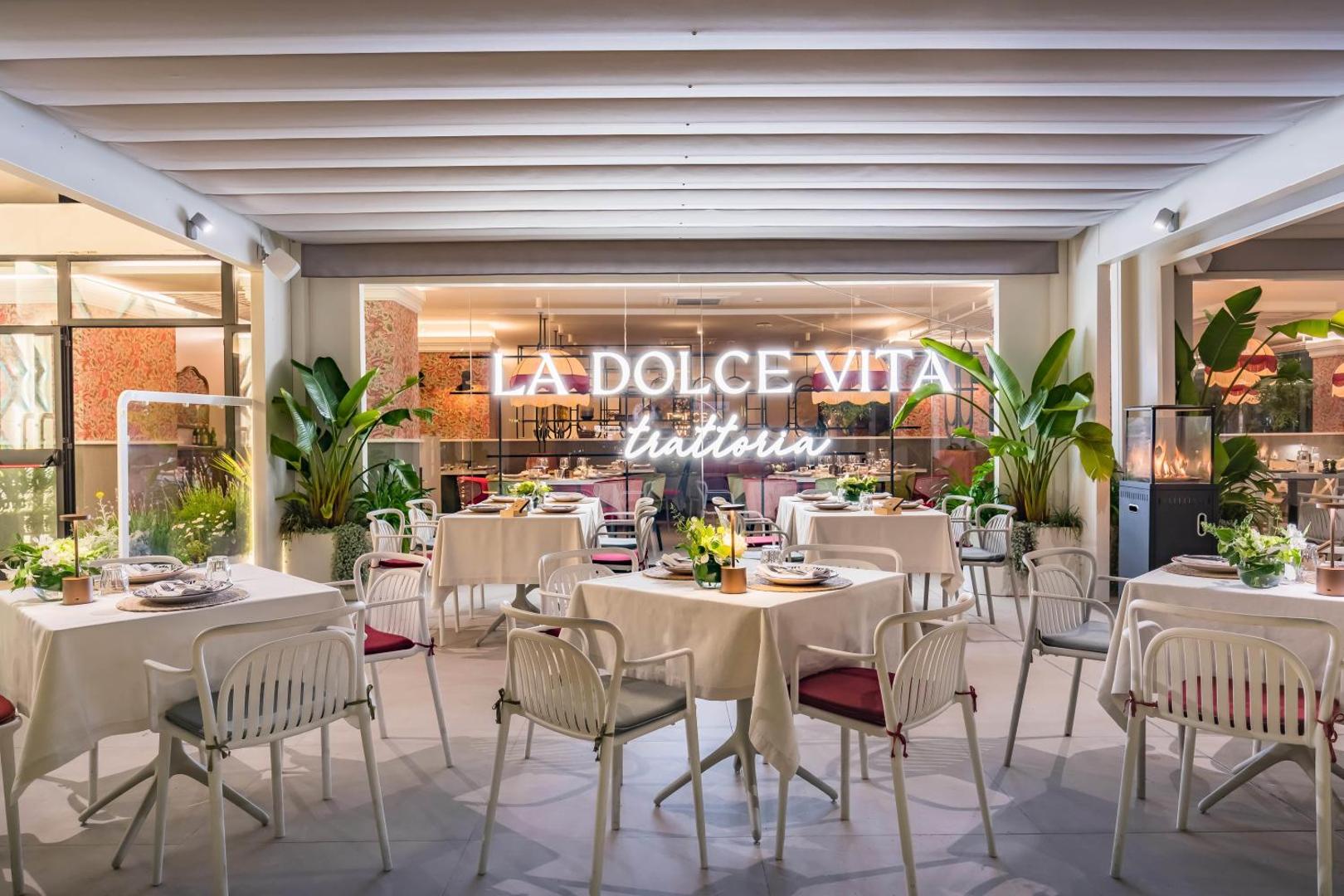 La Dolce Vita trattoria restorāna āra terase Occidental Puerto Banus viesnīcā ar klātiem galdiem un vakara apgaismojumu