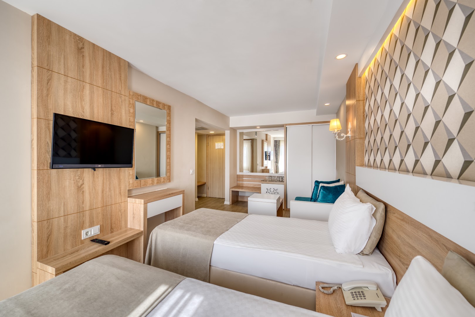 Sealife Family Resort Hotel numura interjers ar divām gultām, sienas televizoru un koka apdares elementiem