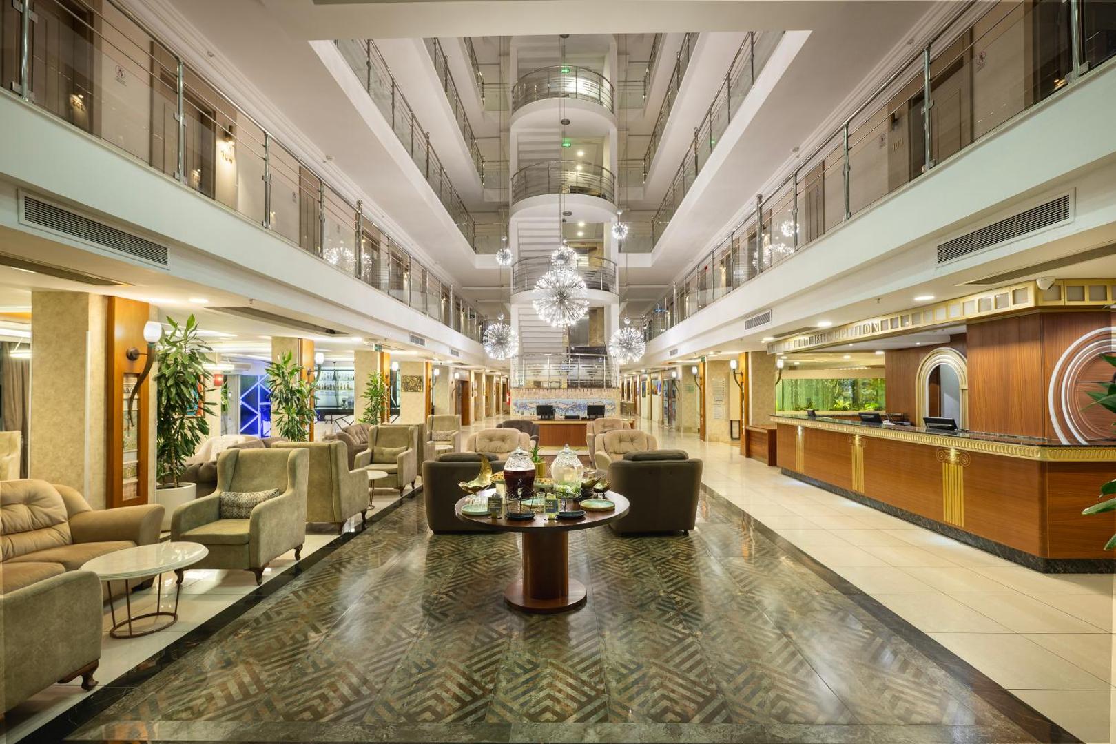 Sealife Family Resort Hotel plašais vestibils ar recepcijas leti, atpūtas zonu un modernām lustrām Antaljas piekrastē, Turcijā