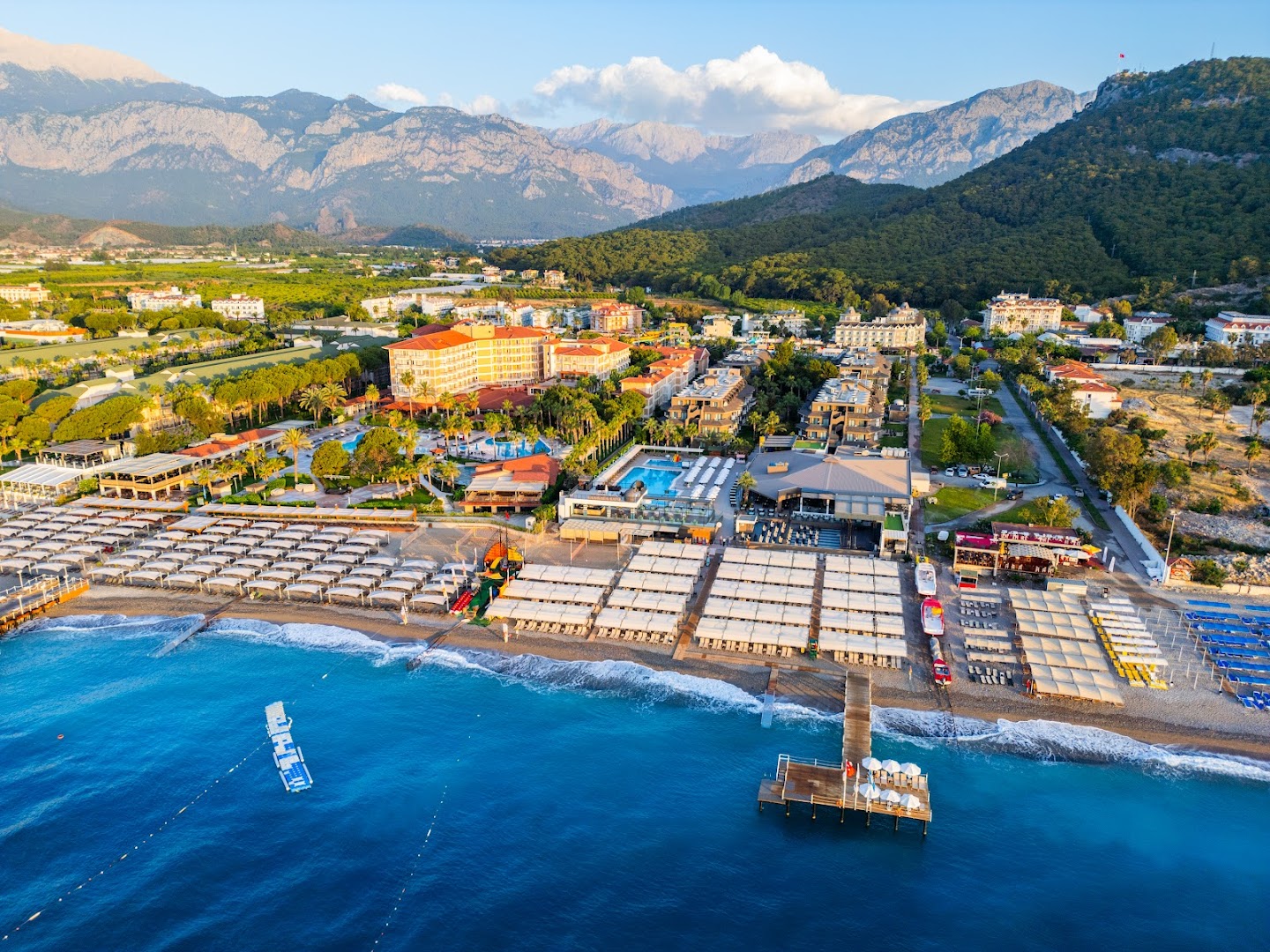Sailor's Beach Club plašā teritorija no augšas — baseini, pludmales saulessargi, piestātne un iespaidīgā Tauru kalnu grēda