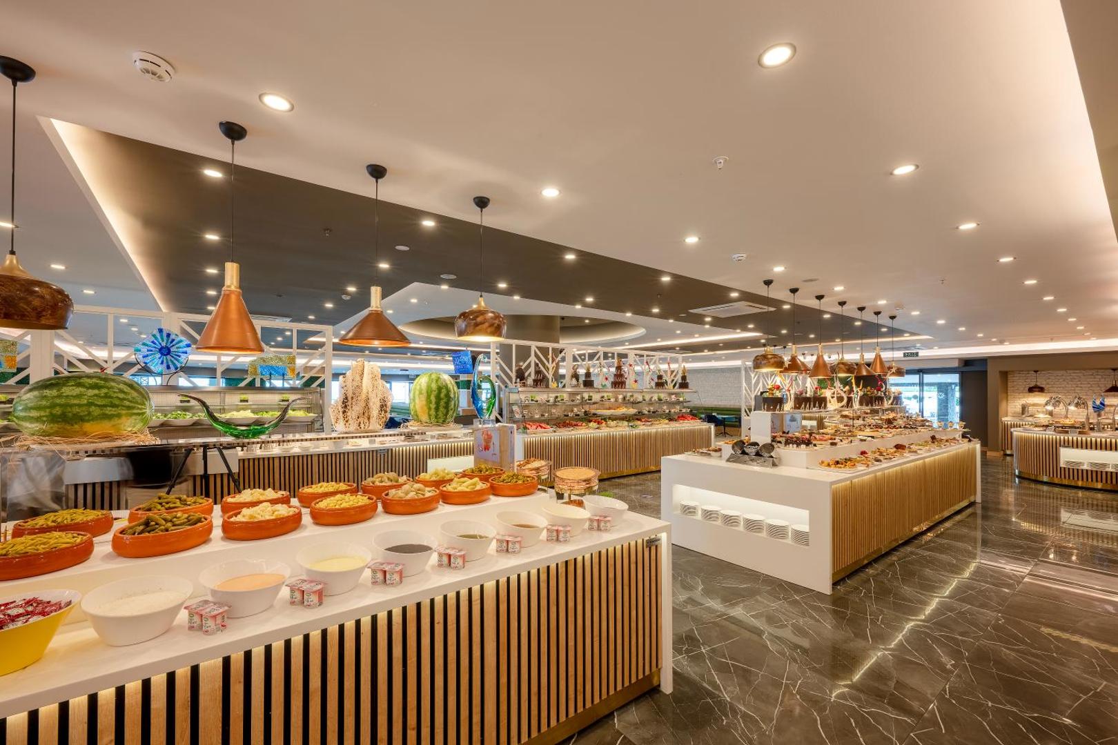 Sailor's Beach Club galvenā restorāna bufetes zona ar plašu ēdienu izvēli, uzkodām un augļiem modernā interjerā