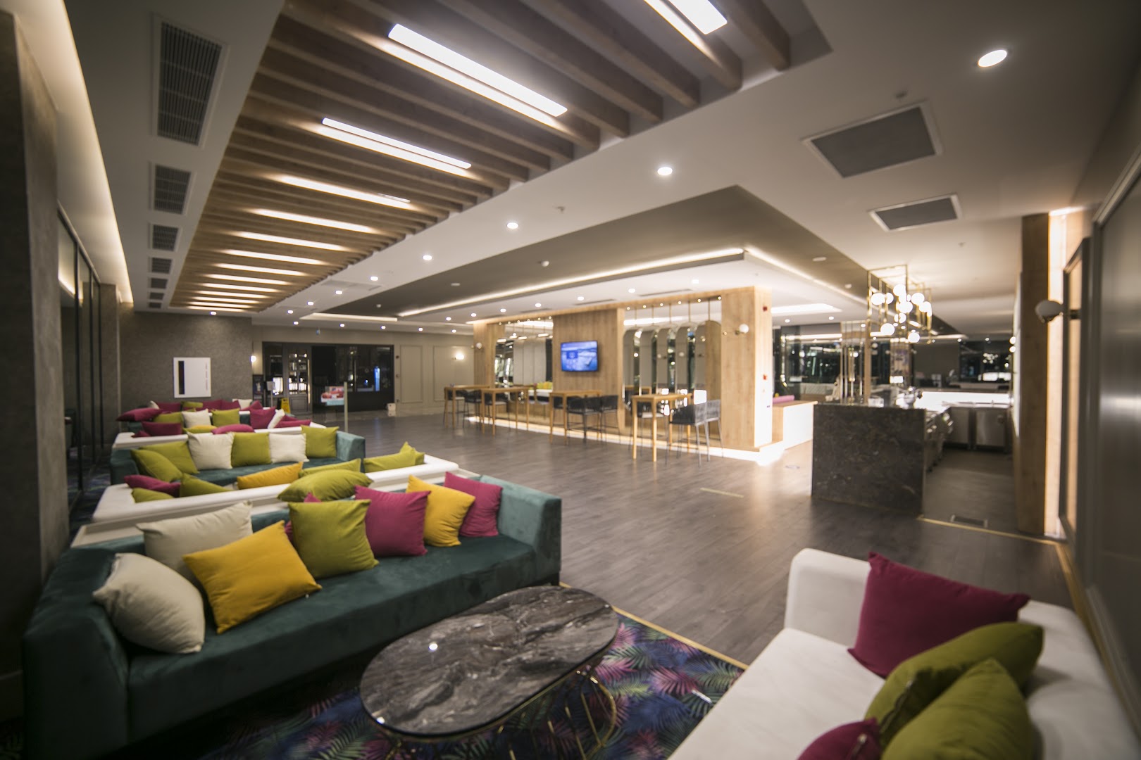 Sailor's Beach Club viesnīcas lobby atpūtas zona ar krāsainiem dīvāniem un modernu apgaismojumu Kemeras reģionā, Turcijā