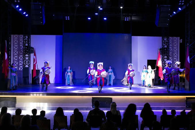 Vakara šovs Sailor's Beach Club amfiteātrī ar dejotājiem tradicionālos tērpos un Turcijas karogiem uz skatuves