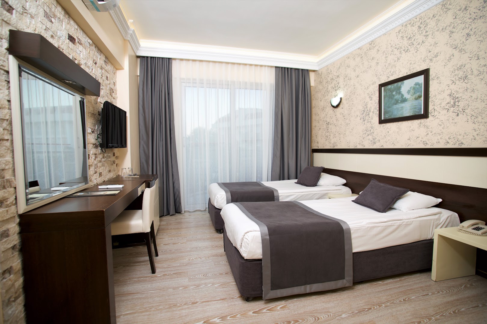 Camyuva Beach Hotel divvietīgs numurs ar atsevišķām gultām, modernu apgaismojumu un dekoratīvu akmens sienu Turcijā