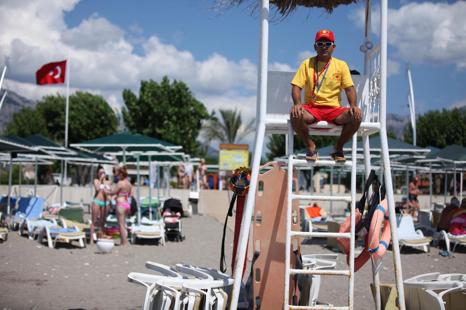 Glābējs savā postenī Camyuva Beach Hotel pludmalē — drošības aprīkojums un sauļošanās krēsli fonā Kemeras kūrortā