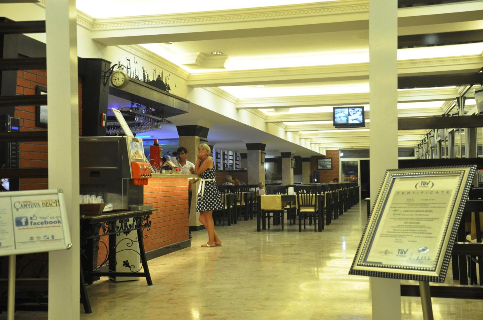 Camyuva Beach Hotel restorāna zona un bārs ar galdiņiem un bufetes elementiem, kur tiek pasniegta starptautiska virtuve