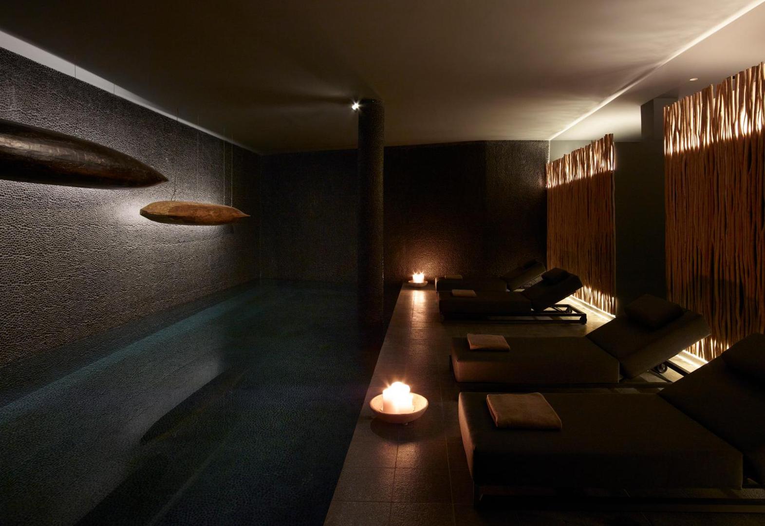 Cayo Exclusive Resort and Spa spa centra iekšējais baseins ar relaksācijas krēsliem, sveču gaismu un tumšu, atmosfērisku dizainu Elundā