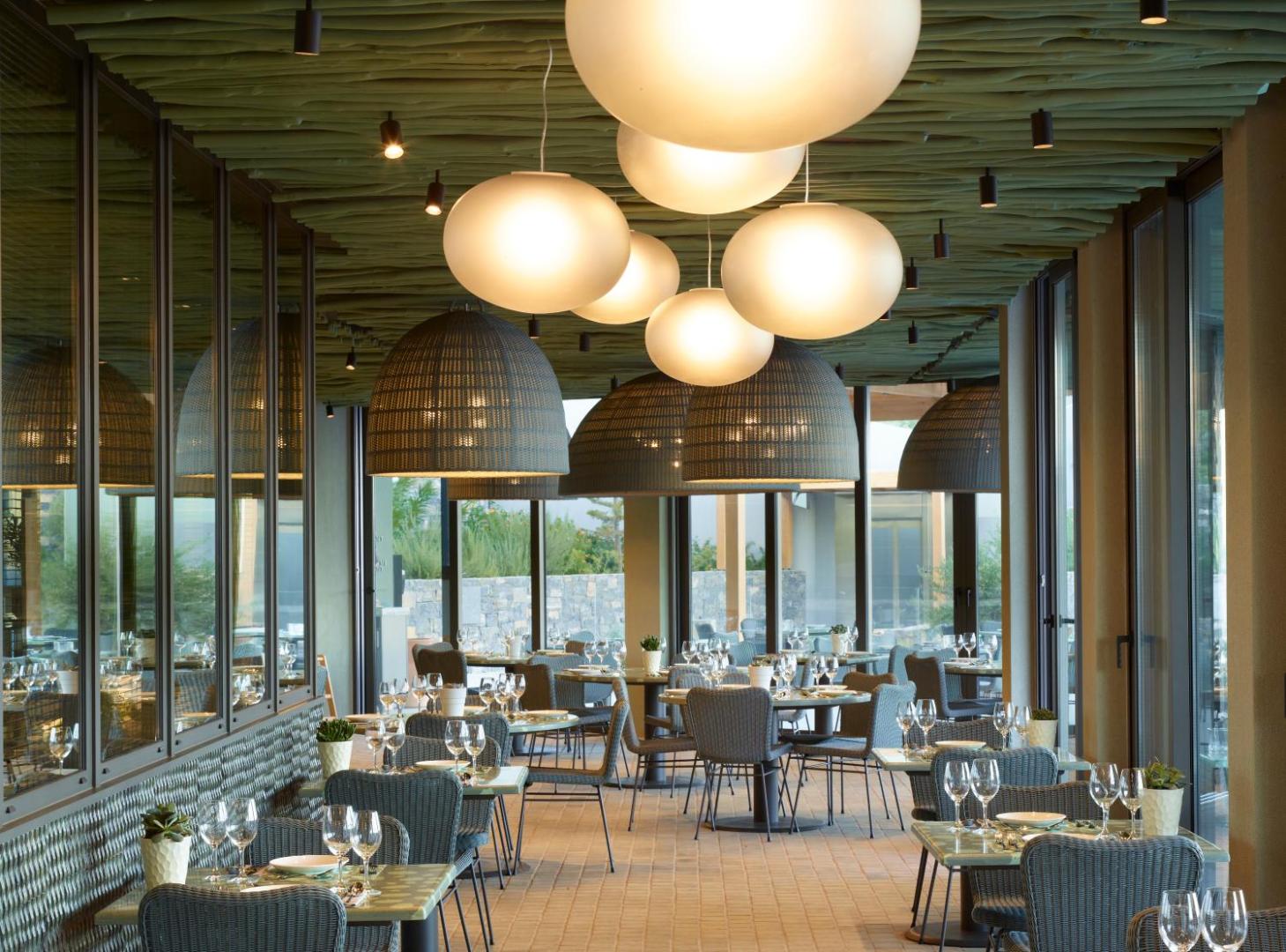 Cayo Exclusive Resort and Spa modernais restorāna interjers ar dizaina gaismekļiem un skatu caur lielajiem logiem
