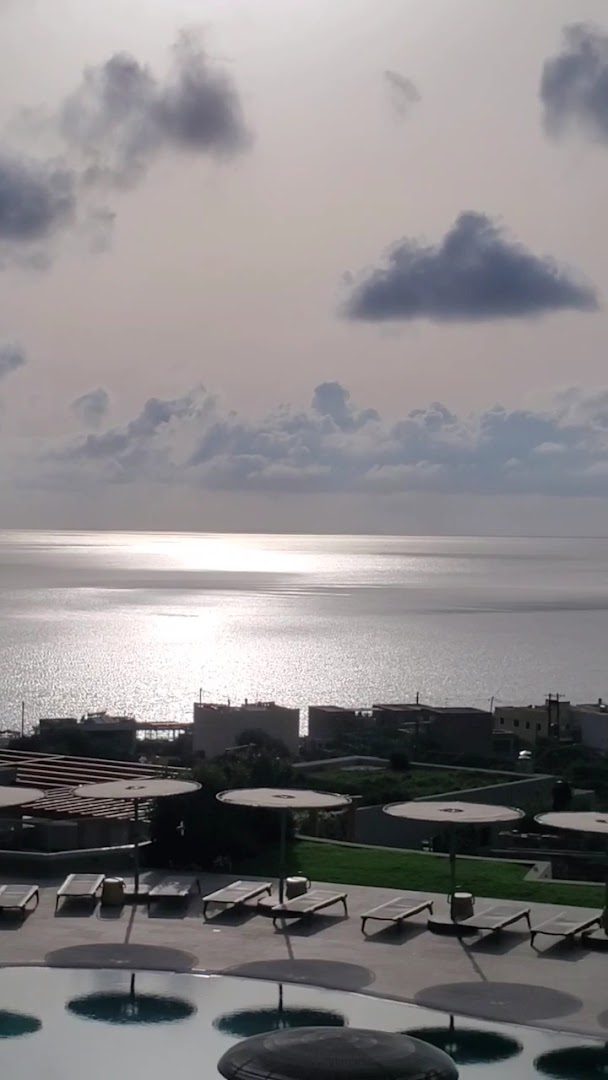 Saulrieta atspulgs jūrā no Cayo Exclusive Resort and Spa terases ar sauļošanās krēsliem un mierīgu atmosfēru