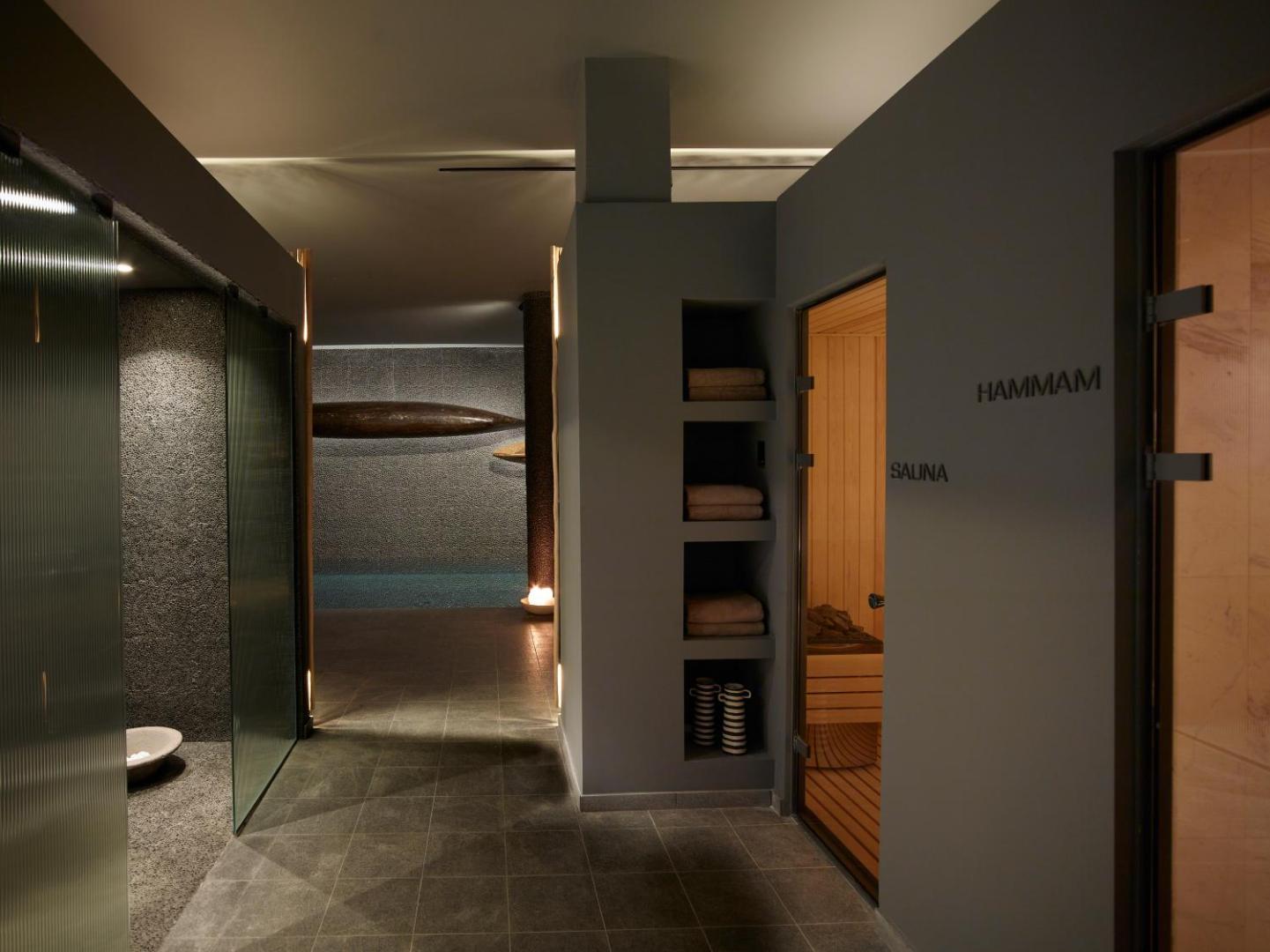 Cayo Exclusive Resort and Spa spa zonas ieeja pirtīs, rādot saunu un hammam telpas ar modernu apgaismojumu un pelēku apdari