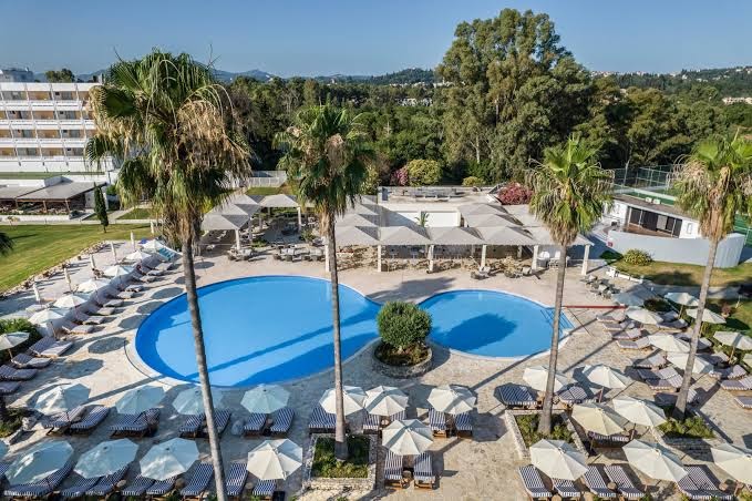 Kerkyra Blue Hotel & Spa teritorijas skats no augšas ar diviem baseiniem, palmām un plašu sauļošanās zonu Korfu