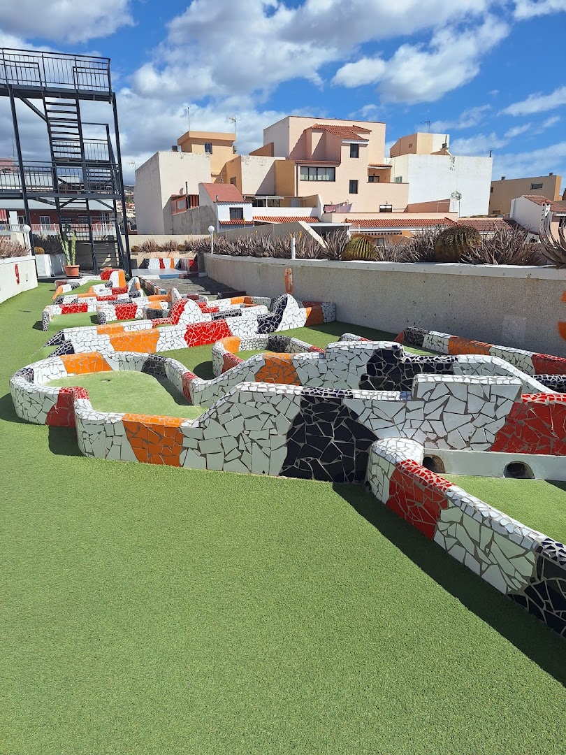 Vigilia Park Apartamentos minigolfa trases ar mozaīkas rakstu un mākslīgo zālienu uz jumta terases Tenerifē — pilsētas ēku fons