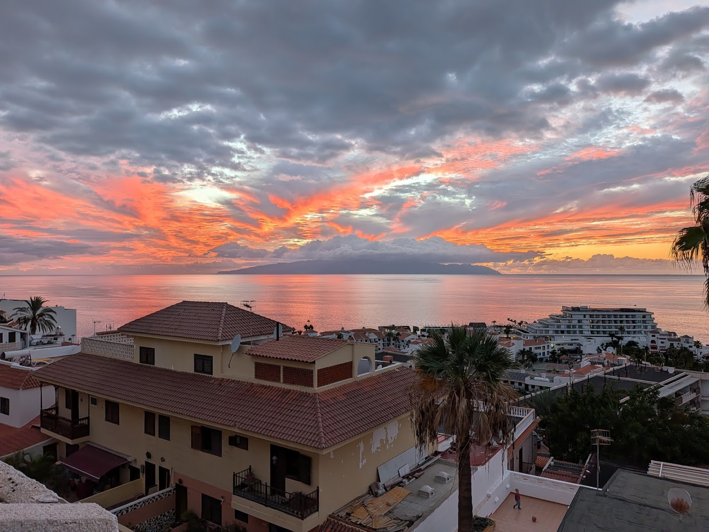 Skats no Vigilia Park Apartamentos terases uz saulrietu pār okeānu un kaimiņu salu Puertodesantjago pilsētā Tenerifē