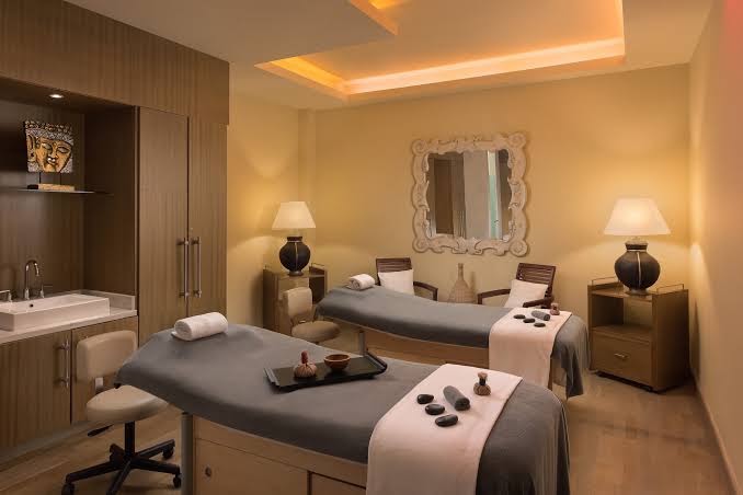 Tivoli La Caleta Tenerife Resort spa masāžas telpa ar divām kušetēm, siltu apgaismojumu un relaksējošu dekoru pāru procedūrām.