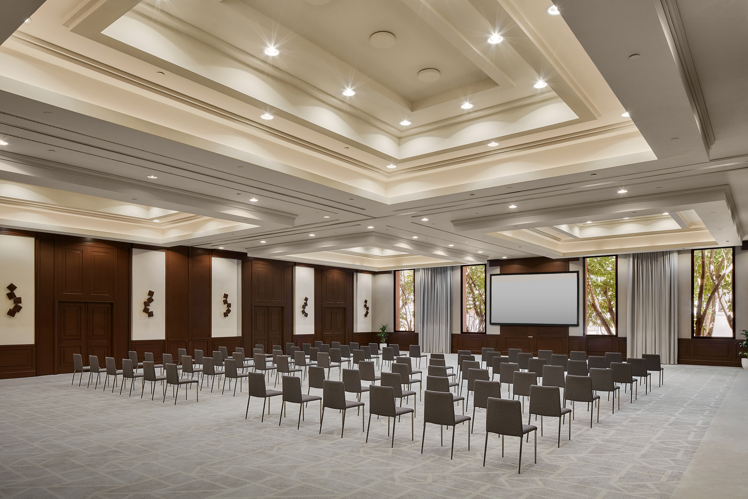 Tivoli La Caleta Tenerife Resort plaša konferenču zāle ar krēslu rindām, augstiem griestiem un prezentāciju ekrānu Tenerifē