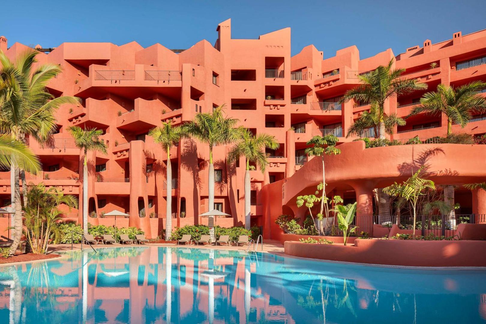 Tivoli La Caleta Tenerife Resort raksturīgā terakotas fasāde ar balkoniem un baseinu priekšplānā — Tenerifes kūrorta arhitektūras paraugs