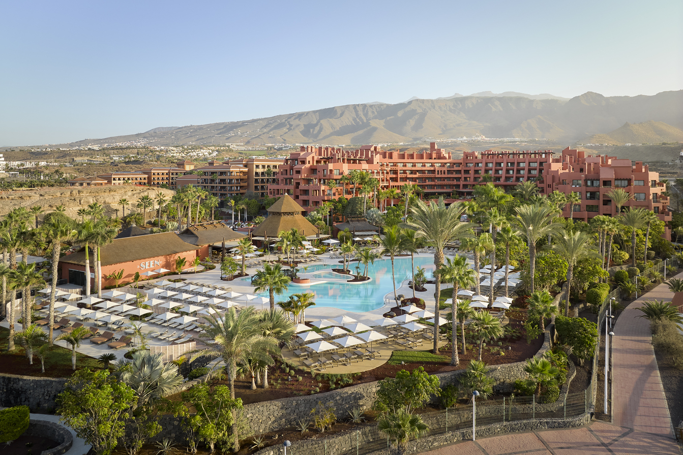 Tivoli La Caleta Tenerife Resort plašā teritorija ar galveno baseinu, restorānu zonu un kalnu fonu saulainā pēcpusdienā