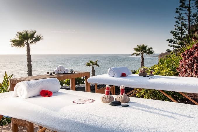 Tivoli La Caleta Tenerife Resort spa procedūru vieta piekrastē ar skatu uz okeānu, masāžas galdiem un palmām