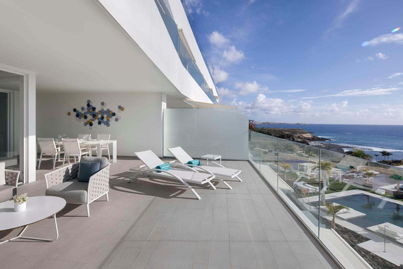 Royal Hideaway Corales Suites plaša terase ar atpūtas mēbelēm un skatu uz piekrasti un baseinu zonu Tenerifē