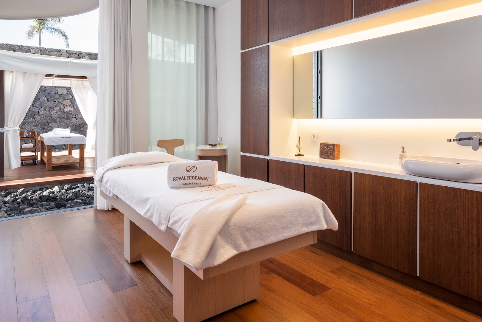 Royal Hideaway Corales Suites spa procedūru numurs ar masāžas galdu un koka apdari — skats uz privātu āra terasi