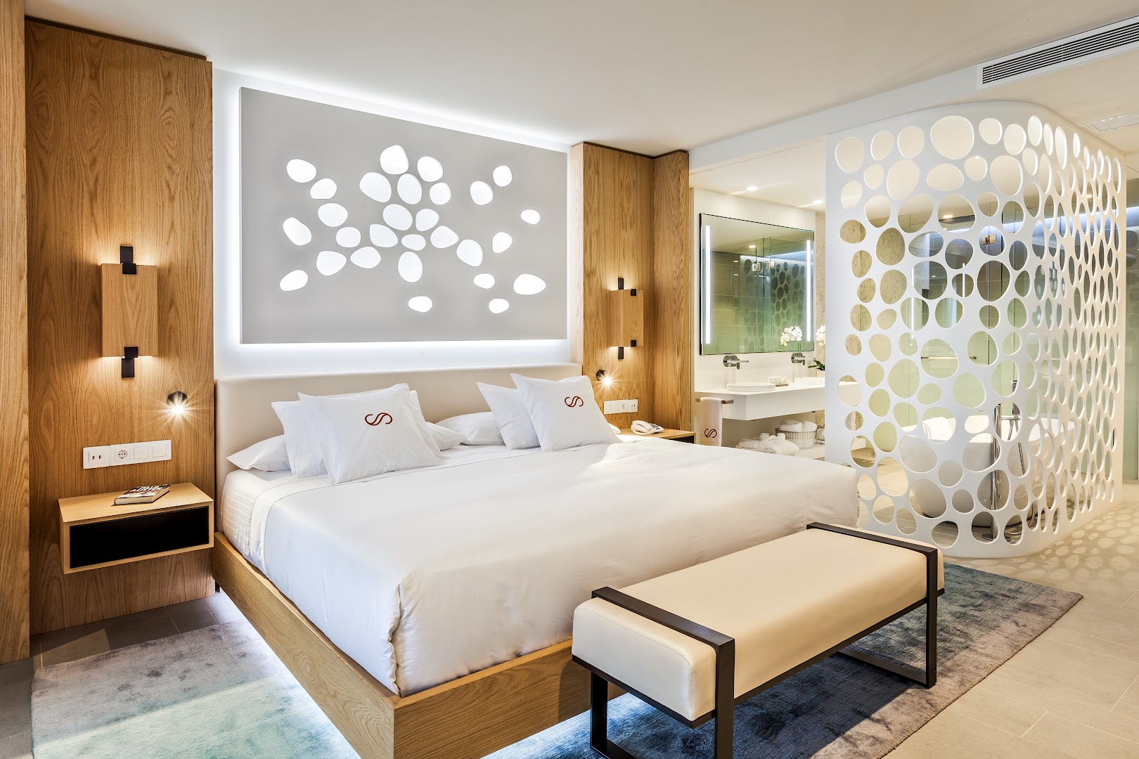 Royal Hideaway Corales Suites luksusa numura interjers ar lielu gultu, koka apdari un atvērta plānojuma vannasistabu Tenerifē