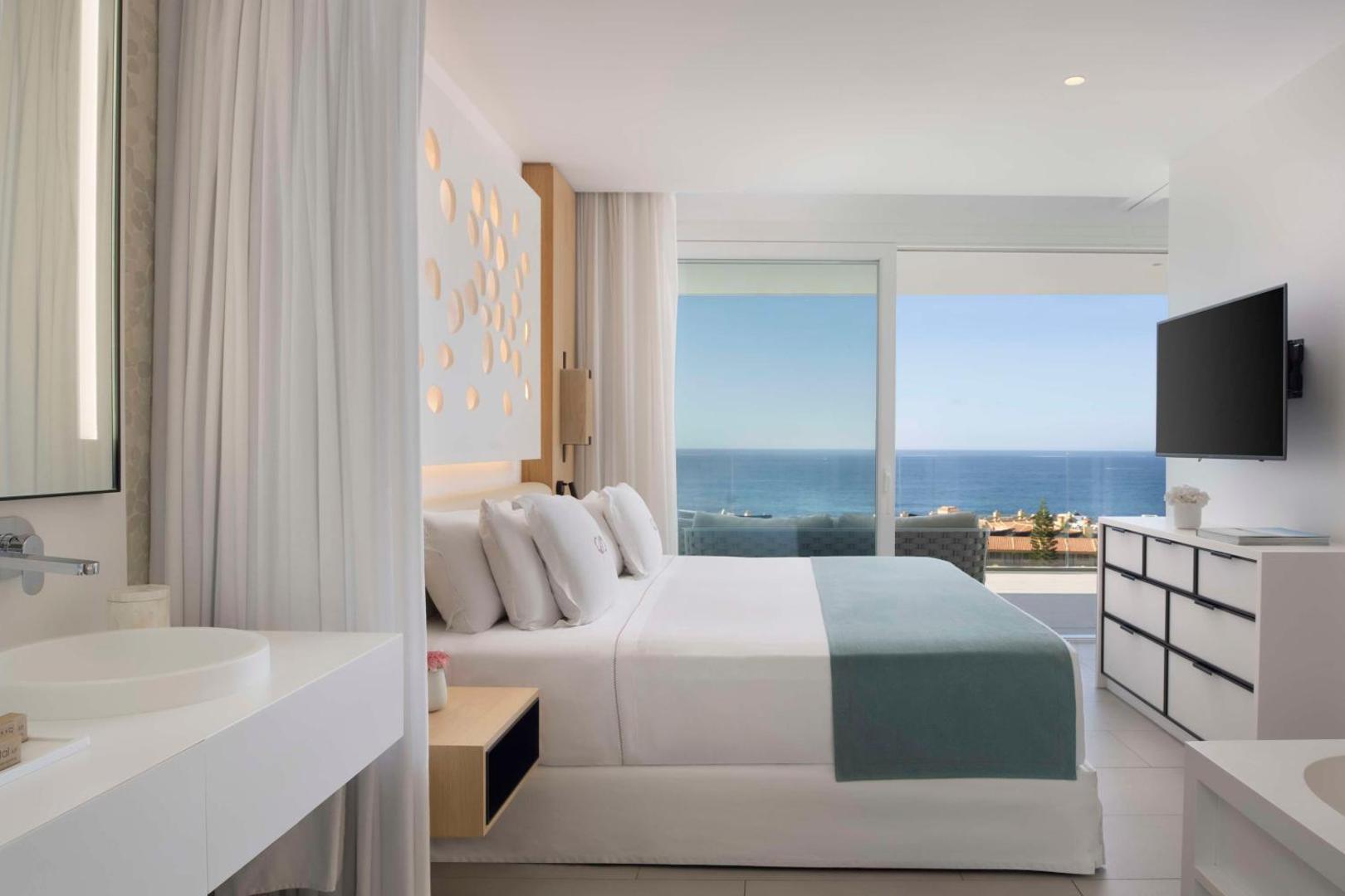 Royal Hideaway Corales Suites guļamistaba ar skatu uz okeānu — balts interjers, lieli logi un tieša izeja uz balkonu Tenerifē