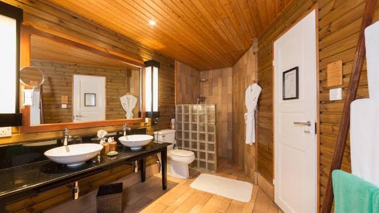 Kuredu Island Resort & Spa bungalo vannas istaba ar koka sienām, divām izlietnēm un modernu dušas zonu