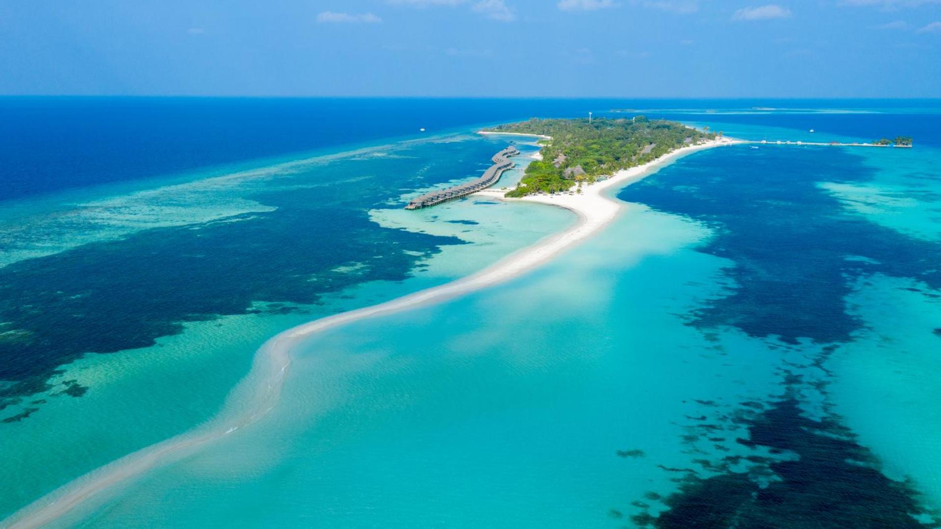 Kuredu Island Resort & Spa panorāmas skats no putna lidojuma uz Maldivu salu, balto smilšu strēli un tirkīza lagūnu