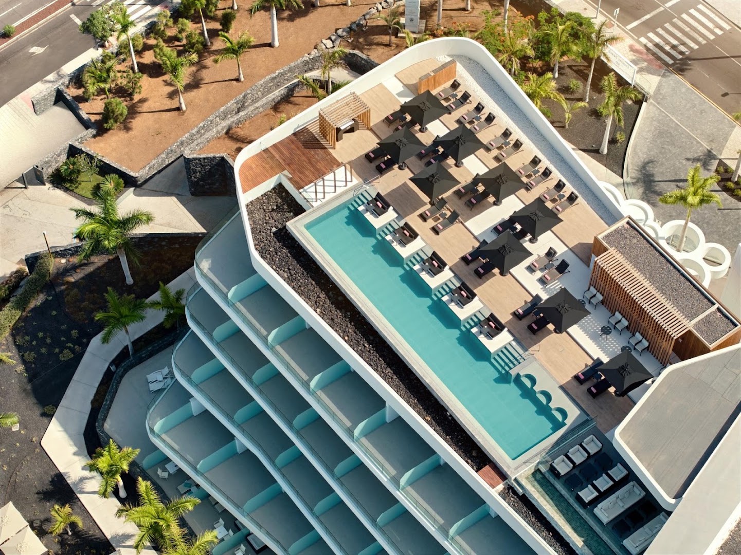 Skats no augšas uz Royal Hideaway Corales Beach jumta terasi ar baseinu, saulessargiem un sauļošanās krēsliem Tenerifē