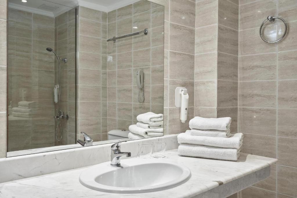 Sandy Beach Resort numura vannas istaba ar gaišām flīzēm, marmora virsmu, dušu un svaigiem dvieļiem.