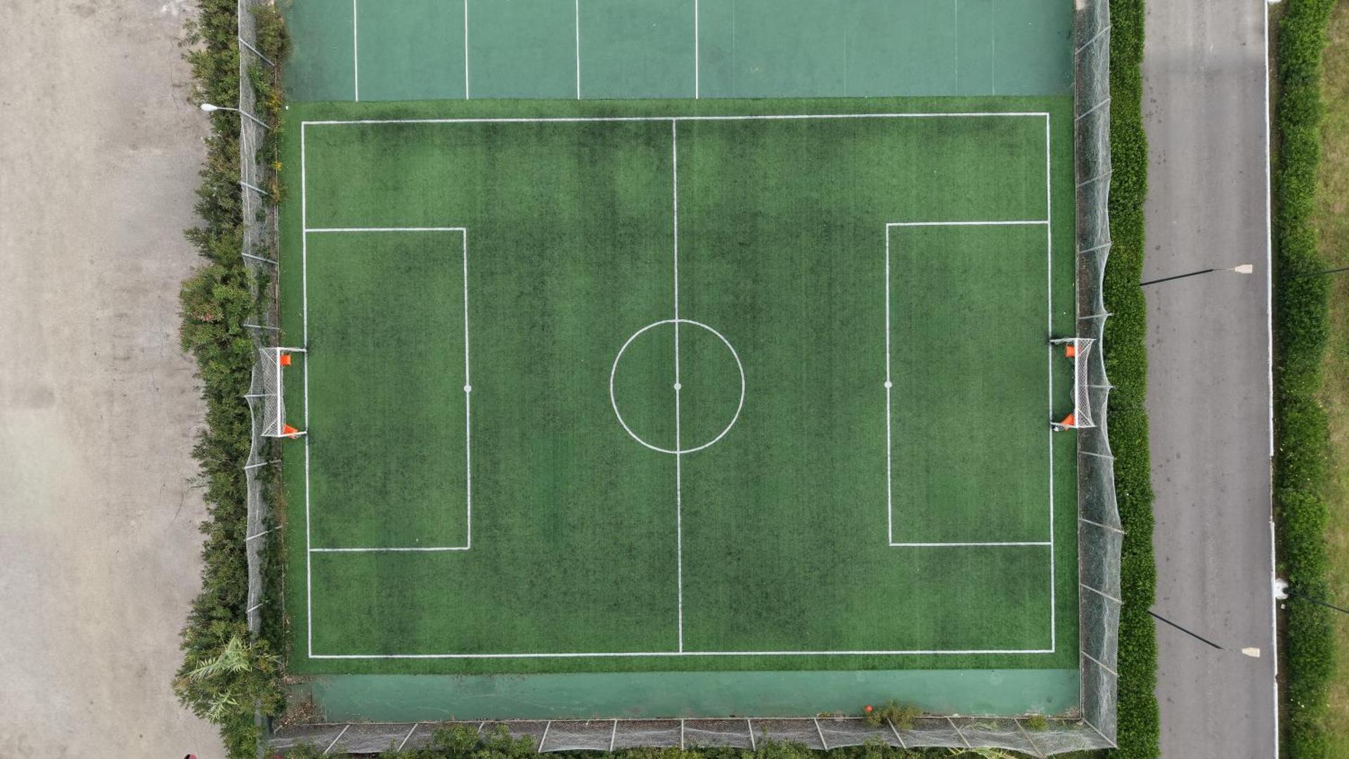 Sandy Beach Resort sporta infrastruktūra — futbola laukums ar mākslīgo zālienu un vārtiem, skats no augšas uz kūrorta aktīvās atpūtas zonu.