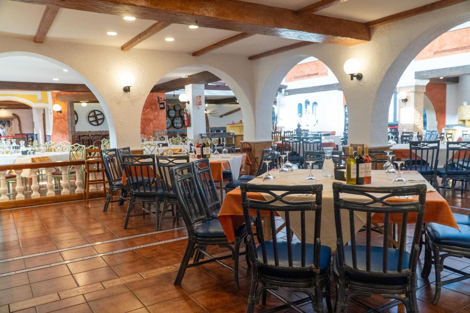 Park Club Europe viesnīcas restorāna iekštelpas ar arkām un klātiem galdiem — tradicionāls interjers ar koka elementiem un flīžu grīdu