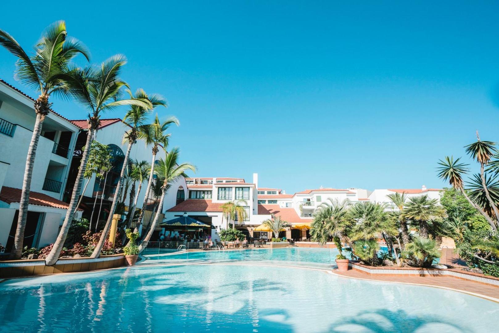 Park Club Europe galvenais āra baseins ar palmām un sauļošanās zonu Tenerifē — plaša teritorija ar atpūtas krēsliem un bāru