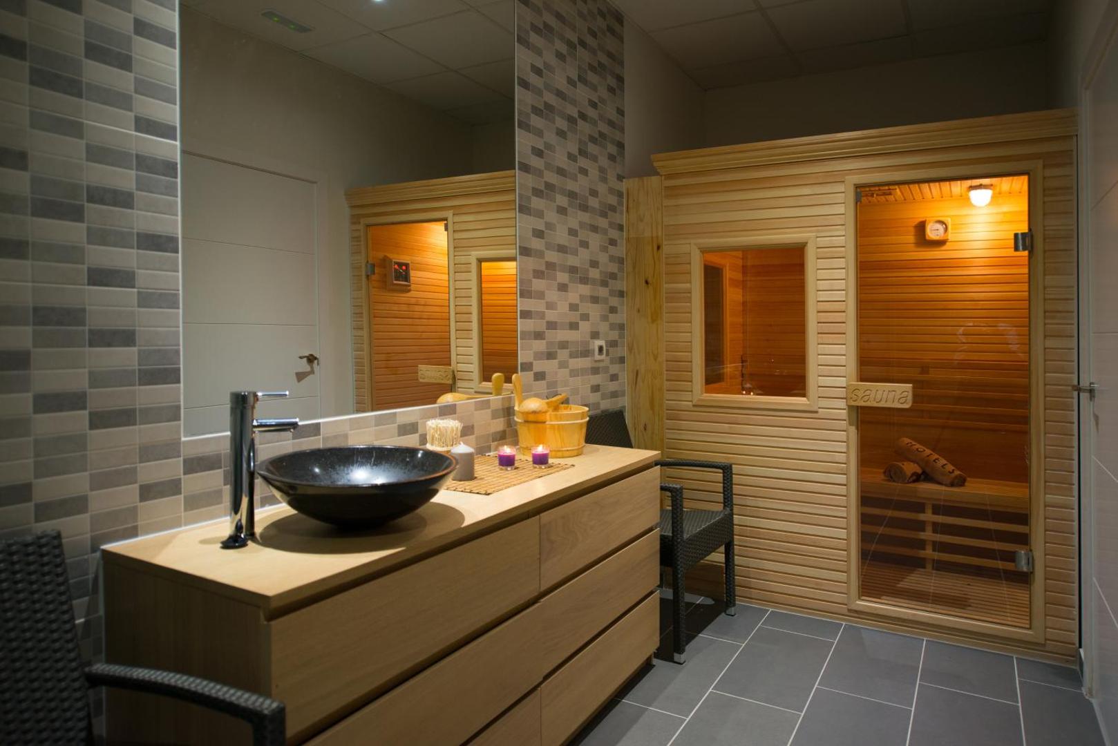 Viesnīcas Ole Tropical Tenerife spa zonas sauna un ģērbtuve ar koka apdari un modernu izlietni Tenerifē.