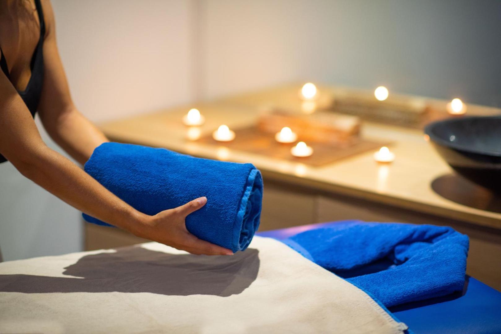 Ole Tropical Tenerife spa centra masāžas telpa ar svecēm un ziliem dvieļiem relaksējošai atpūtai Tenerifes kūrortā.