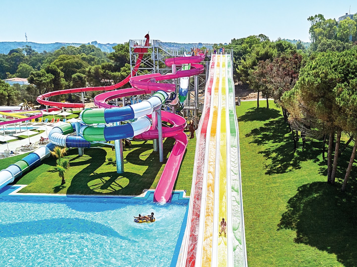 Liels akvaparks ar krāsainiem slidkalniņiem un baseinu Grecotel Mandola Rosa teritorijā, kas ieskauta zaļojošos kokos un zālājos.