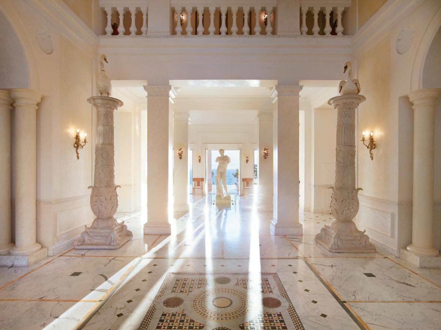 Grecotel Mandola Rosa greznais vestibils ar marmora grīdām, antīkām kolonnām un skulptūrām Peloponēsā, Grieķijā, radot aristokrātisku atmosfēru.