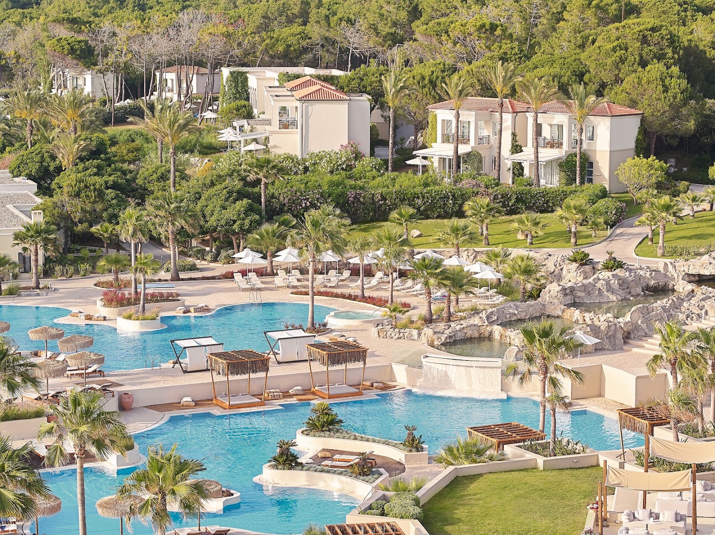 Grecotel La Riviera kūrorta skats no augšas uz plašo baseinu kompleksu, dārzu un villām Peloponēsā, Grieķijā — palmas un atpūtas zonas