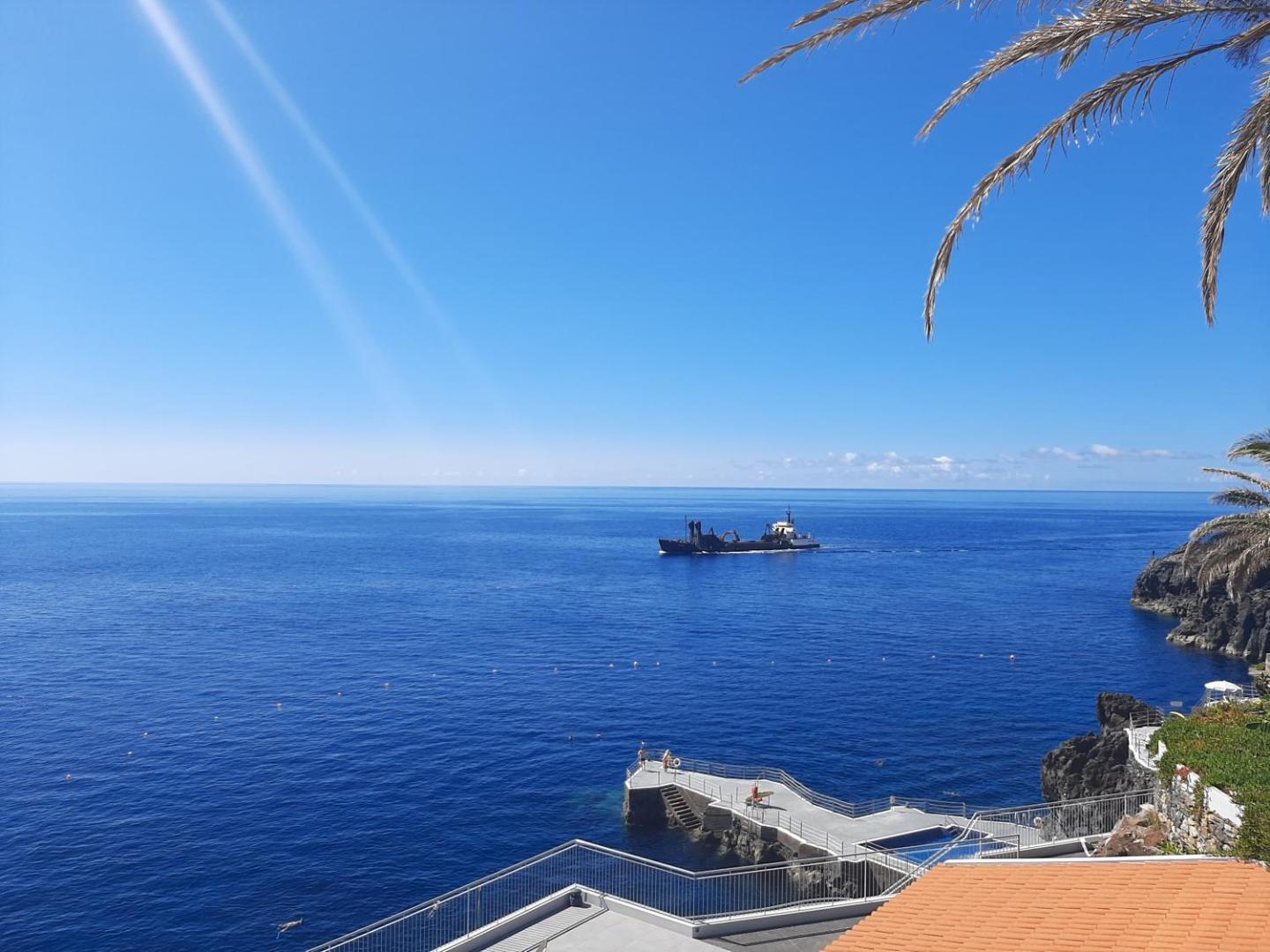 Skats no Rocamar Lido Resort uz okeānu ar kuģi tālumā un betona platformu peldēšanai pie klintīm