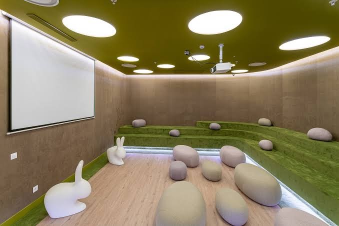 Mediterranean Palace atpūtas telpa ar mīkstiem sēžammaisiem, projekcijas ekrānu un zaļiem pakāpieniem atpūtai