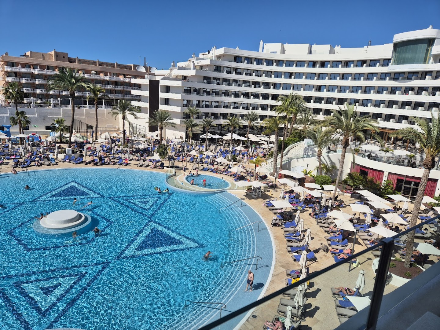 Mediterranean Palace āra baseins dienas laikā ar atpūtniekiem un saulessargiem — skats no augšas uz viesnīcas atpūtas zonu