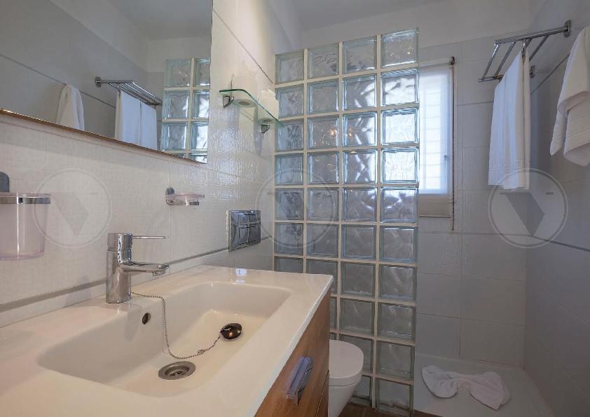 Malibu Park Apartments numura vannasistaba ar izlietni, spoguli un stikla bloku dušas sienu gaišos toņos
