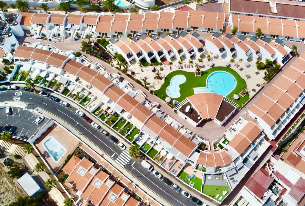 Malibu Park Apartments kompleksa skats no putna lidojuma Tenerifē — balti bungalo, zils āra baseins un labiekārtota atpūtas zona