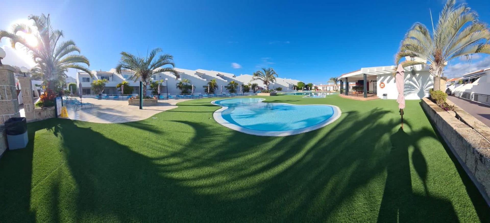 Malibu Park Apartments plašā atpūtas zona ar āra baseinu un mākslīgo zālienu Tenerifē, Spānijā – panorāmas skats uz viesnīcas teritoriju un bungalo tipa ēkām