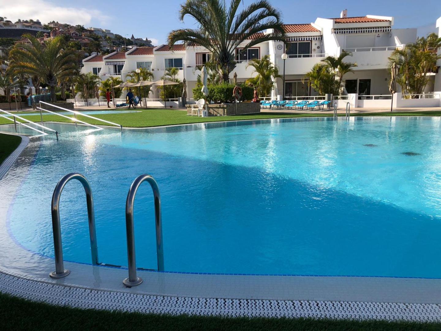 Malibu Park Apartments dzidrais āra baseins ar ērtām kāpnēm un sauļošanās krēsliem – fonā baltas divstāvu apartamentu ēkas