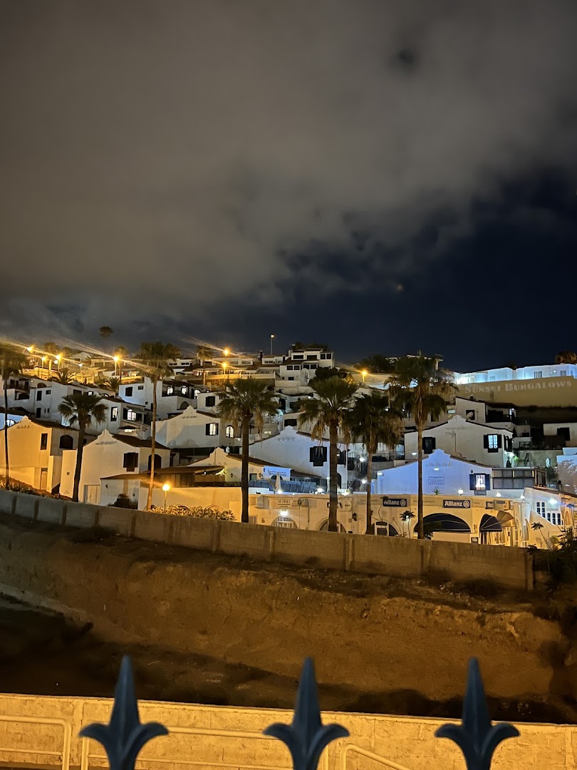 Malibu Park Apartments un Sunset Bungalows komplekss nakts apgaismojumā Tenerifē — izgaismotas baltas ēkas un palmas
