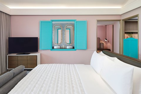 Le Meridien Maldives Resort & Spa numura interjers ar skatu uz vannasistabu caur dekoratīviem tirkīza krāsas slēģiem un modernu dizainu