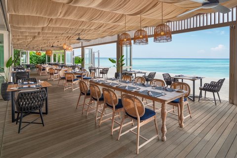 Le Meridien Maldives Resort & Spa restorāns ar koka terasi, stilīgām mēbelēm un skatu uz Indijas okeānu