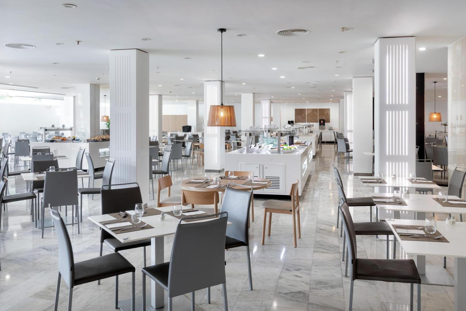 Alexandre Hotel La Siesta plašais un gaišais galvenais restorāns Tenerifē ar modernām mēbelēm, marmora grīdu un bufetes tipa ēdināšanas zonu
